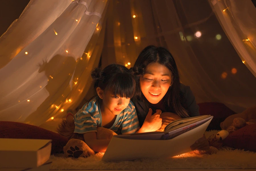 A mom and a little girl read together in a gauzy indoor tent.