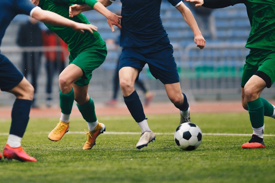 Several men playing competitive soccer, shown from the waist down to emphasize their feet