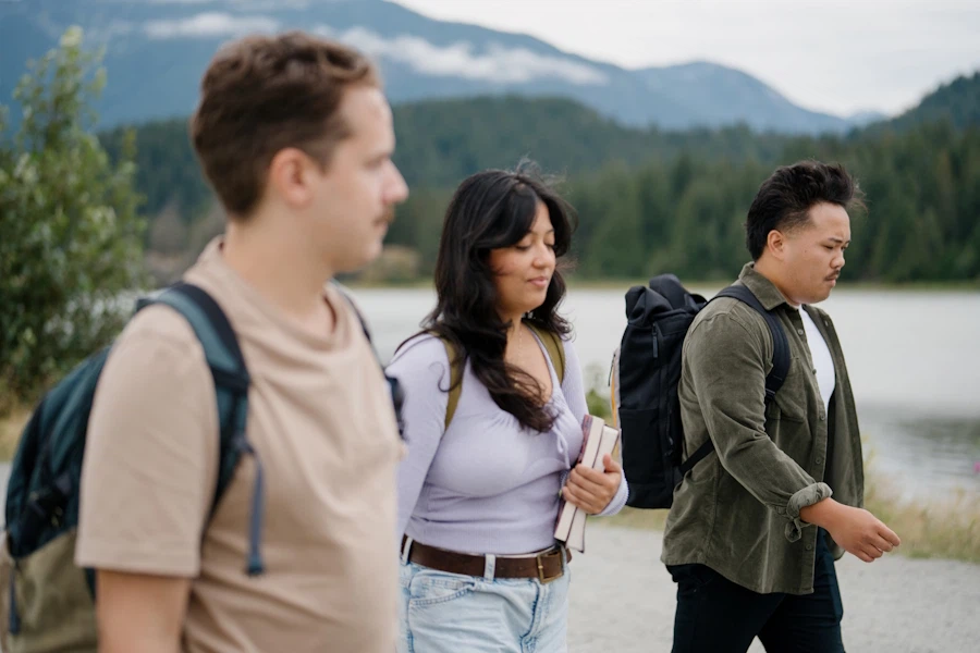 Three people walk abreast down a mountain pathway.