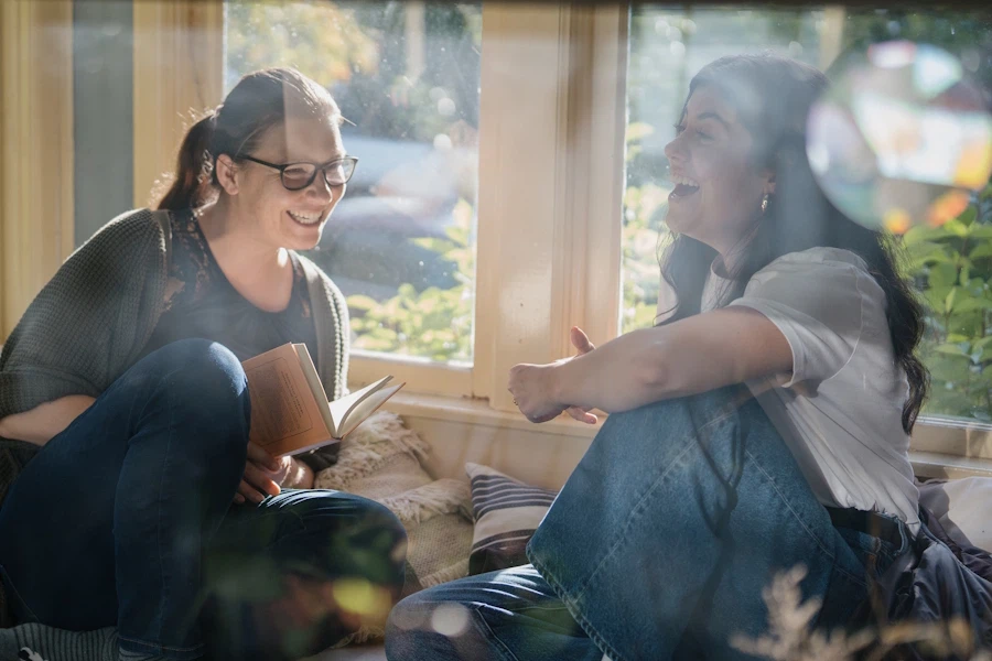 Two young women in a window seat on a sunny summer evening