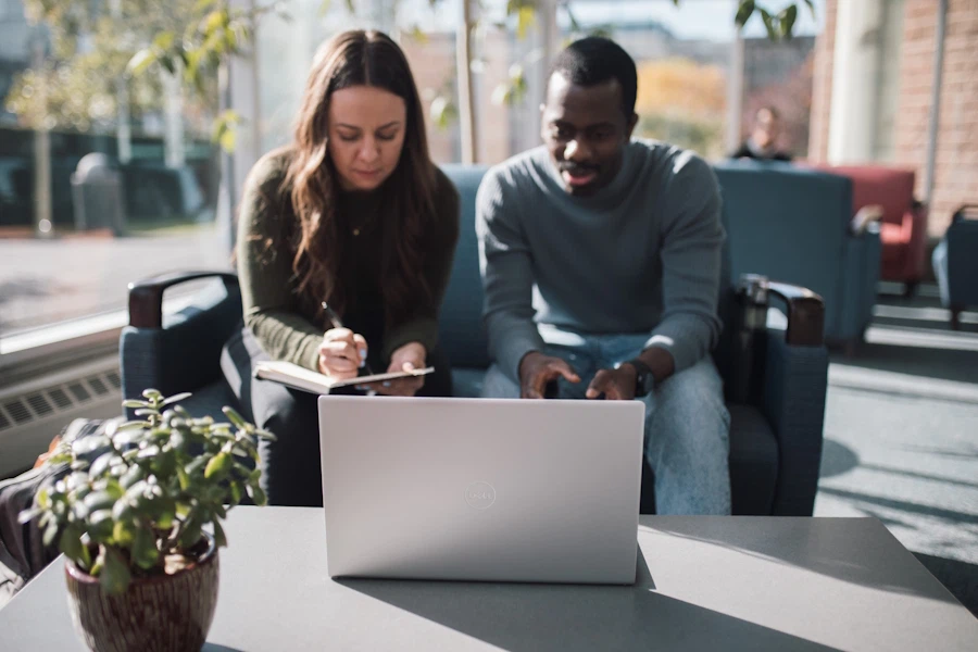 Two students sit looking at a laptop in Regent College's atrium